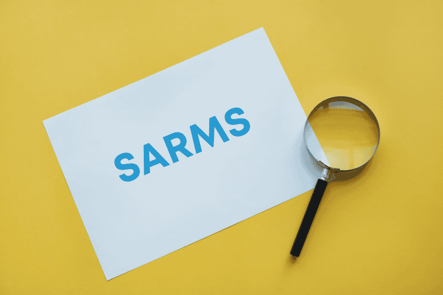 Text reading SARMS on white paper with magnifying glass against yellow background, depicting scientific research context