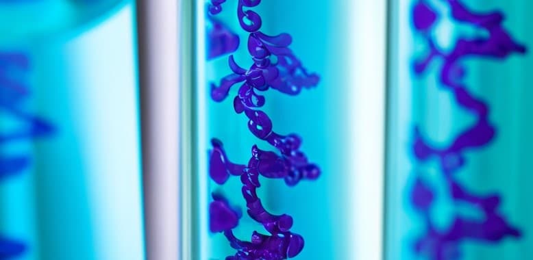 Laboratory vial containing purple research compound in blue solution for scientific analysis