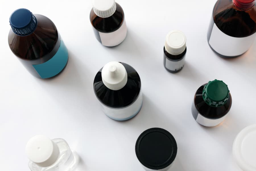 Various amber laboratory vials containing research-grade compounds arranged on white surface, displaying different cap colors