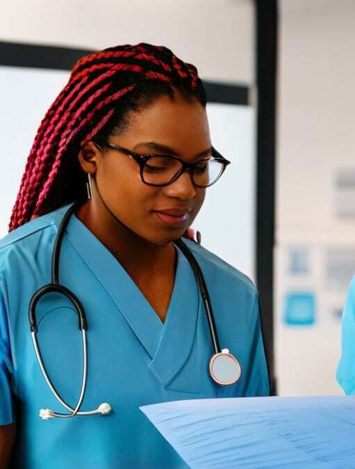 Healthcare professional in blue scrubs with stethoscope reviewing research documentation in clinical laboratory setting