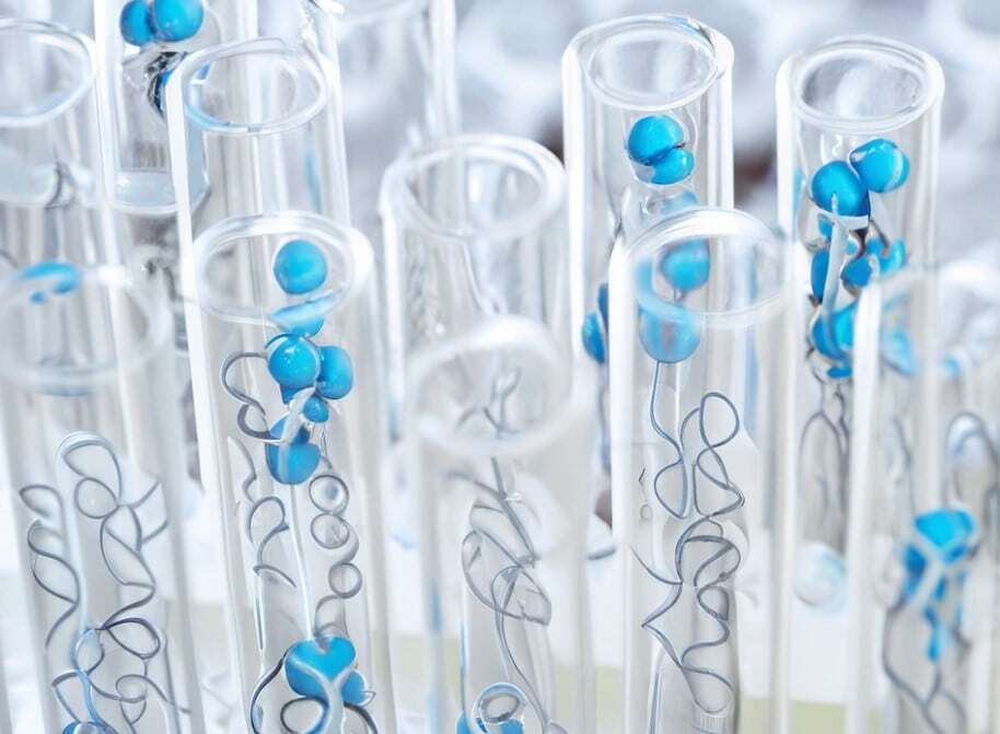 Laboratory test tubes containing blue research compound samples with spiral wire markers for research identification